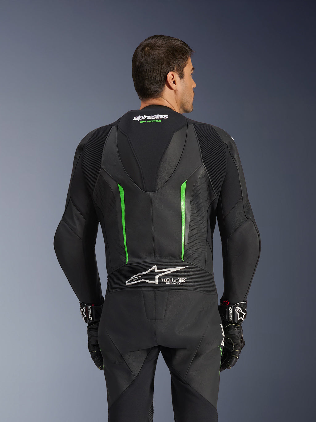 Mono de cuero Alpinestars GP Force V2 - 1 pieza, negro y verde, vista trasera con joroba aerodinámica, logotipo Tech-Air Ready, zonas de cuero perforado y paneles elásticos de acordeón para carreras de motos