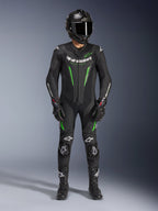 Piloto de motociclismo con el traje de cuero Alpinestars GP Force V2 de una pieza en negro y verde, combinado con un casco de fibra de carbono y guantes de carreras, con paneles de cuero perforados y logotipos blancos de Alpinestars, equipamiento profesional para pista y conducción deportiva