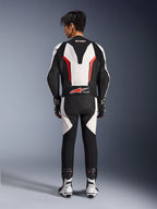 Traje de cuero Alpinestars GP Force V2 de 1 pieza, traje de carreras para moto, blanco, negro y rojo flúor, vista posterior del modelo usando el traje con botas y guantes de carreras, con joroba aerodinámica, paneles elásticos de acordeón y logotipo Tech-Air Ready