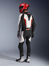 Alpinestars GP Force V2 Leather Suit - 1Piece, White Black Red Fluo, rear view of rider wearing full racing gear, including red helmet, black and white boots and gloves, highlighting the aerodynamic speed hump and ergonomic stretch panels.