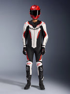 Mono de cuero Alpinestars GP Force V2 de 1 pieza, blanco, negro y rojo flúor, equipamiento completo de carreras que incluye casco rojo, guantes y botas negros, con diseño aerodinámico y logotipos de Alpinestars en el pecho y las rodillas