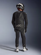 Alpinestars GP Force V2 2-Piece Leather Suit en color negro, vista trasera completa que muestra la joroba aerodinámica y la marca Tech-Air Ready, combinado con casco a juego en blanco y negro y botas de carreras blancas para un rendimiento profesional en pista