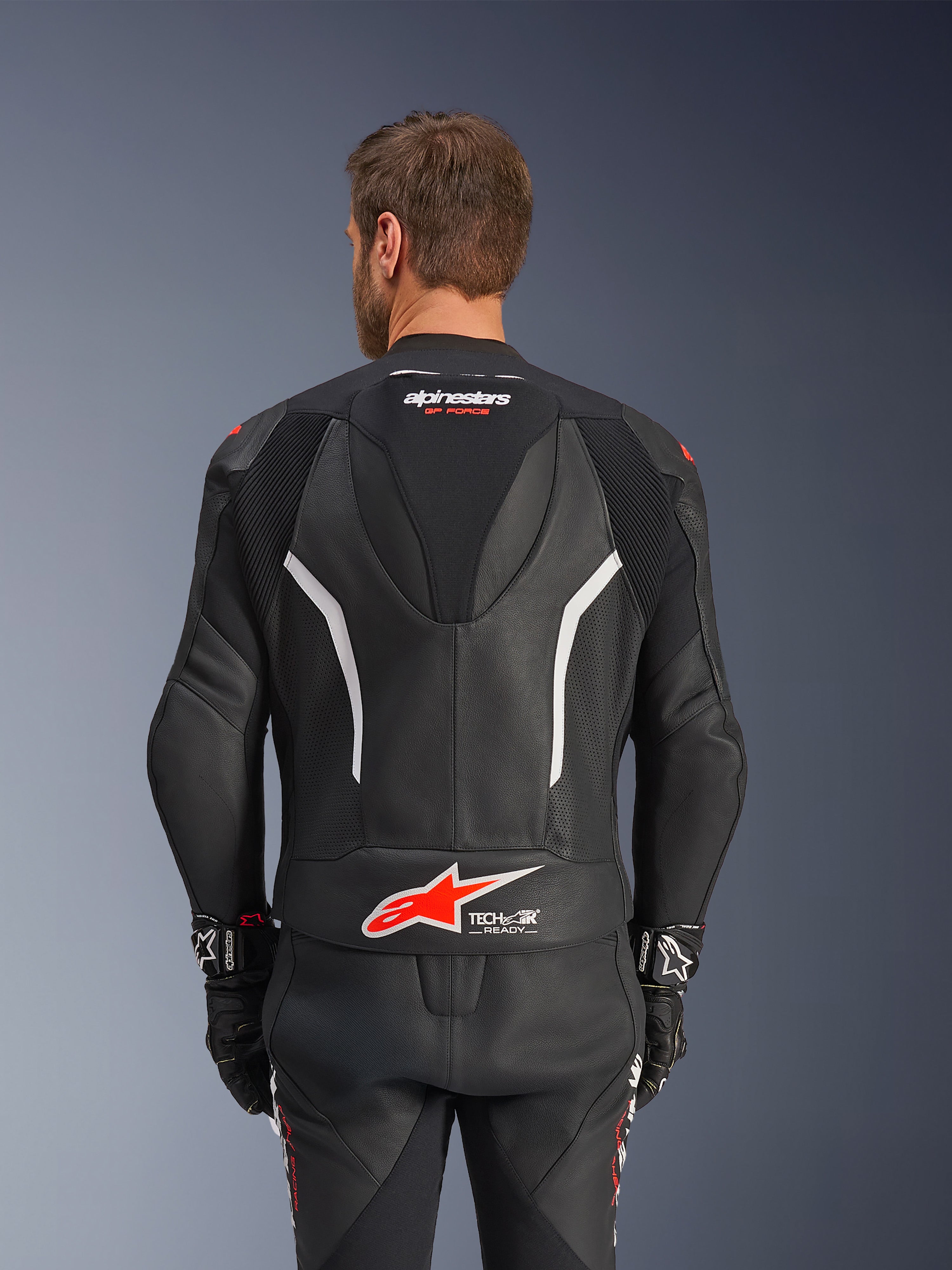 Traje de cuero de 2 piezas Alpinestars GP Force V2, negro, blanco y rojo fluo, vista trasera de la chaqueta de cuero, con el logotipo Tech-Air Ready, detalles en blanco, paneles de cuero perforado y acordeón elástico para movilidad.