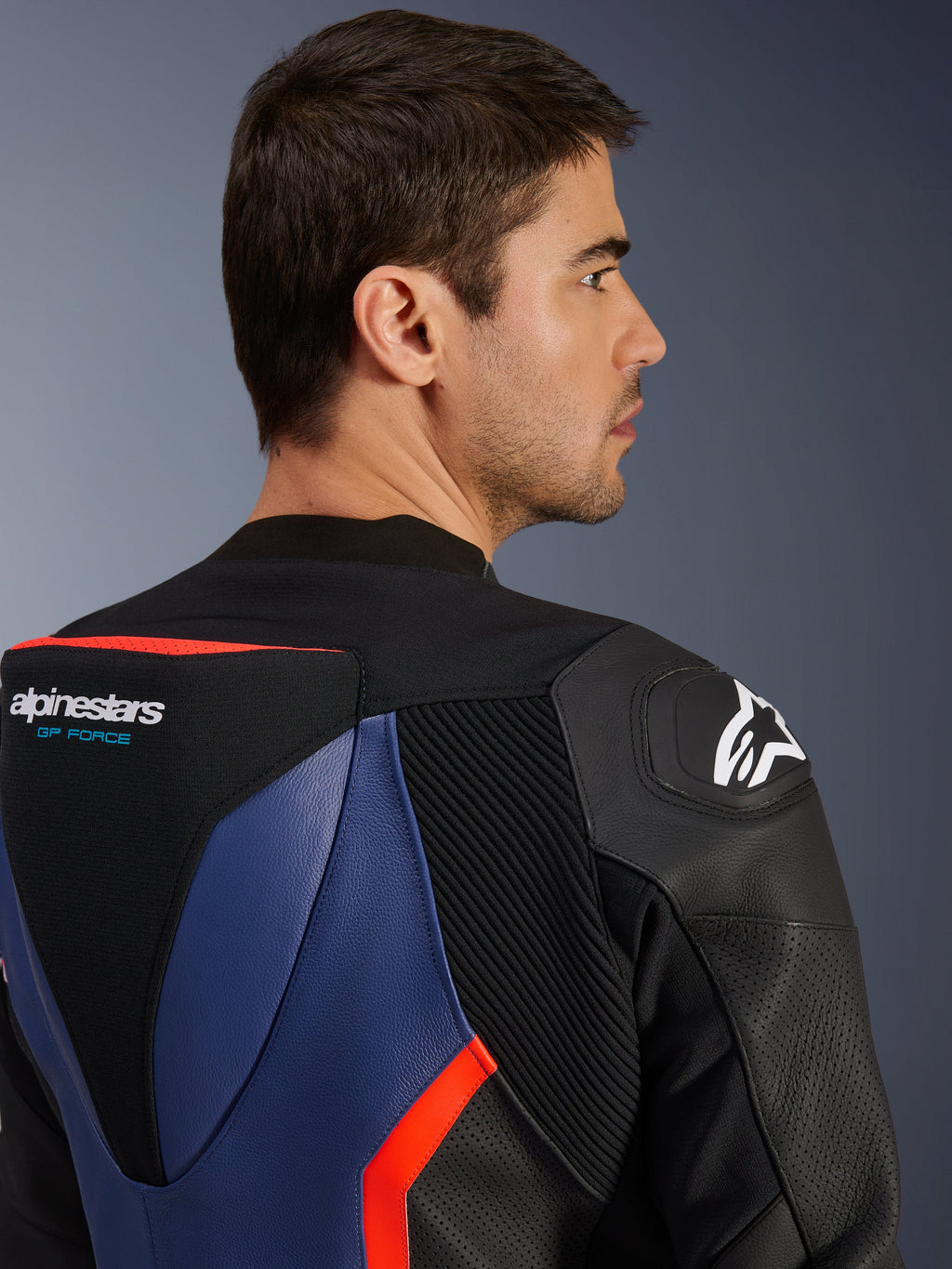 Traje de cuero Alpinestars GP Force V2 de 2 piezas, primer plano de la parte superior de la espalda y el hombro con joroba aerodinámica y logo GP Force, deslizador de hombro DFS, cuero bovino en negro, azul y rojo flúor, paneles perforados y zonas de acordeón, equipamiento profesional para carreras