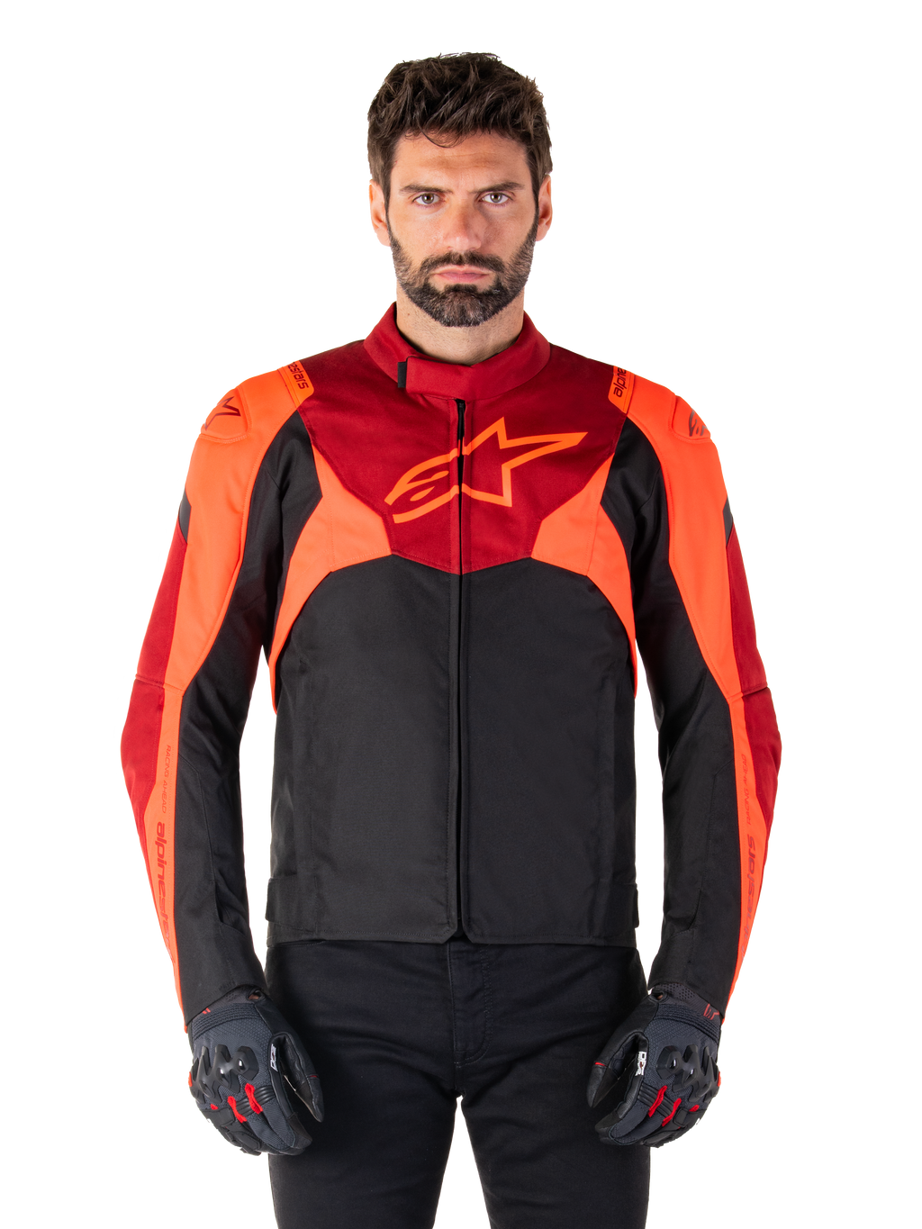 Alpinestars T-Jaws V4 Waterproof Jacket, chaqueta textil de moto deportiva, negra con detalles en rojo flúor y rojo oscuro, lucida por un modelo masculino con guantes a juego, equipamiento técnico con un destacado logotipo de estrella en el pecho.