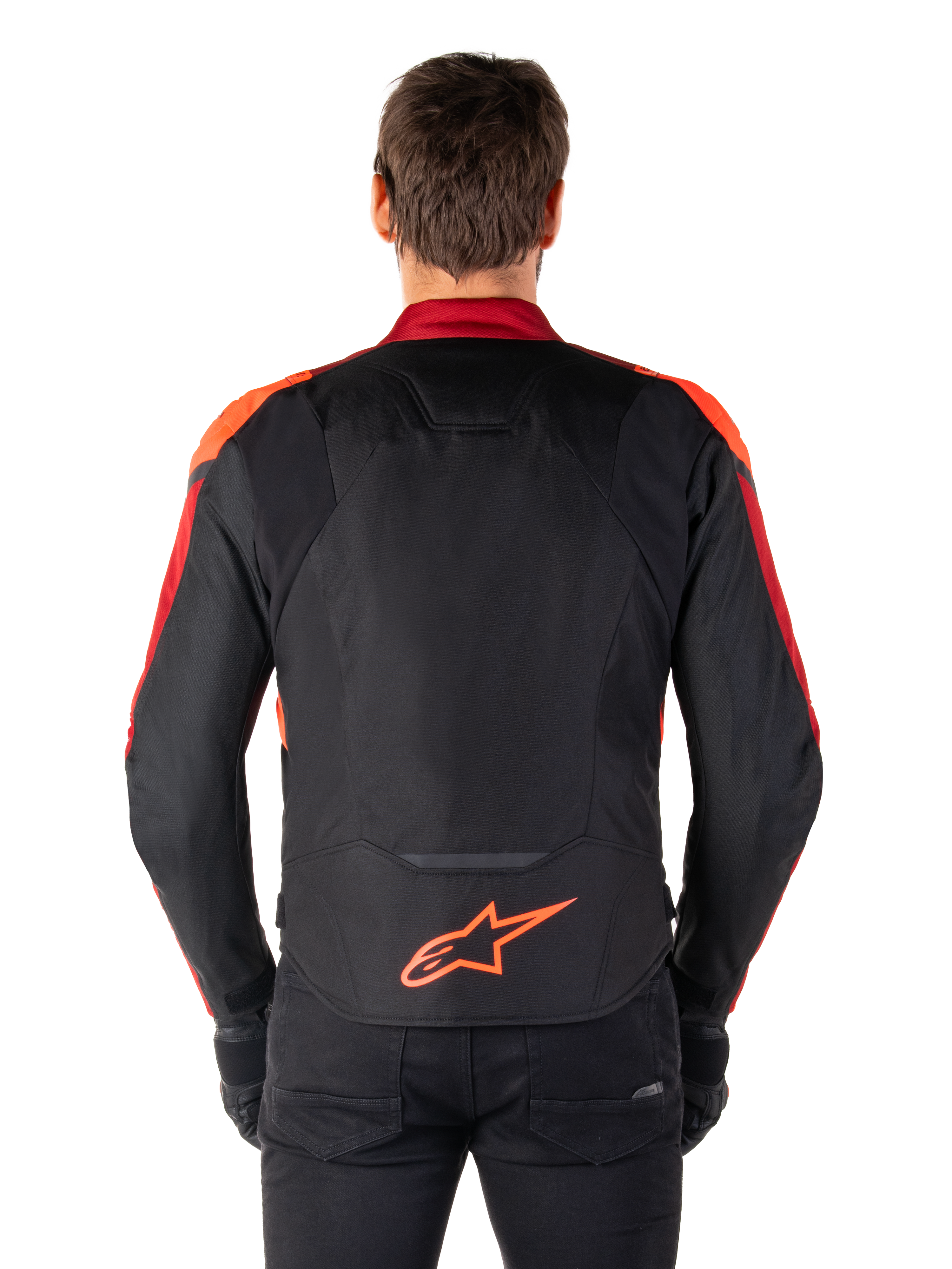 Chaqueta Alpinestars T-Jaws V4 Waterproof, vista trasera, color negro con detalles en rojo flúor y rojo oscuro, logotipo naranja en la parte inferior de la espalda, panel trasero extendido para mayor cobertura al conducir, chaqueta de moto textil deportiva