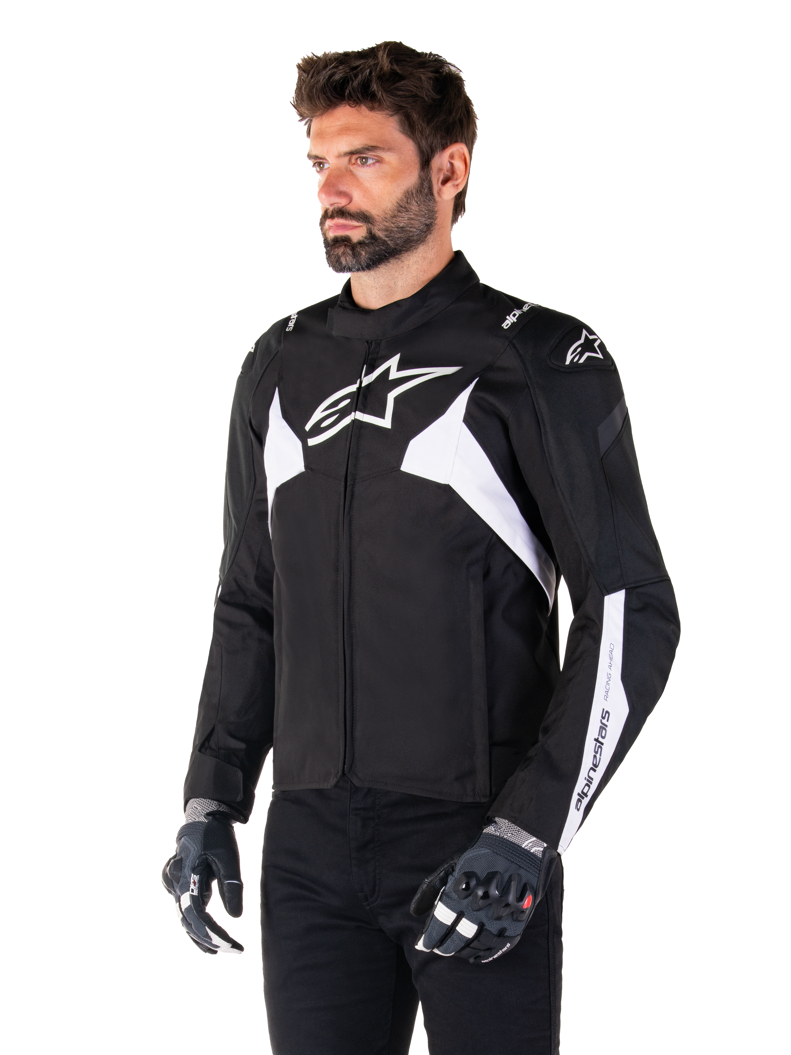 Chaqueta impermeable Alpinestars T-Jaws V4, en negro y blanco, lucida por un modelo con guantes de moto, con destacados logos y detalles de Alpinestars en blanco, chaqueta de moto textil con ajuste deportivo para carretera