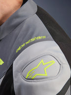 Alpinestars T-Jaws V4 Waterproof Jacket, detail of shoulder with neon yellow Alpinestars logo and wordmark, Black Ice Gray and Dark Gray technical textile, GP Lite shoulder reinforcement.