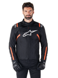 Alpinestars T-SPS V2 Waterproof Jacket, chaqueta impermeable en negro, blanco y rojo flúor, lucida por un modelo masculino con guantes de moto negros, con un gran logotipo de Alpinestars en el pecho y llamativos detalles en naranja en los hombros y las mangas