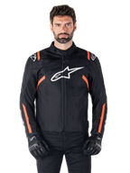 Alpinestars T-SPS V2 Waterproof Jacket, chaqueta impermeable en negro, blanco y rojo flúor, lucida por un modelo masculino con guantes de moto negros, con un gran logotipo de Alpinestars en el pecho y llamativos detalles en naranja en los hombros y las mangas
