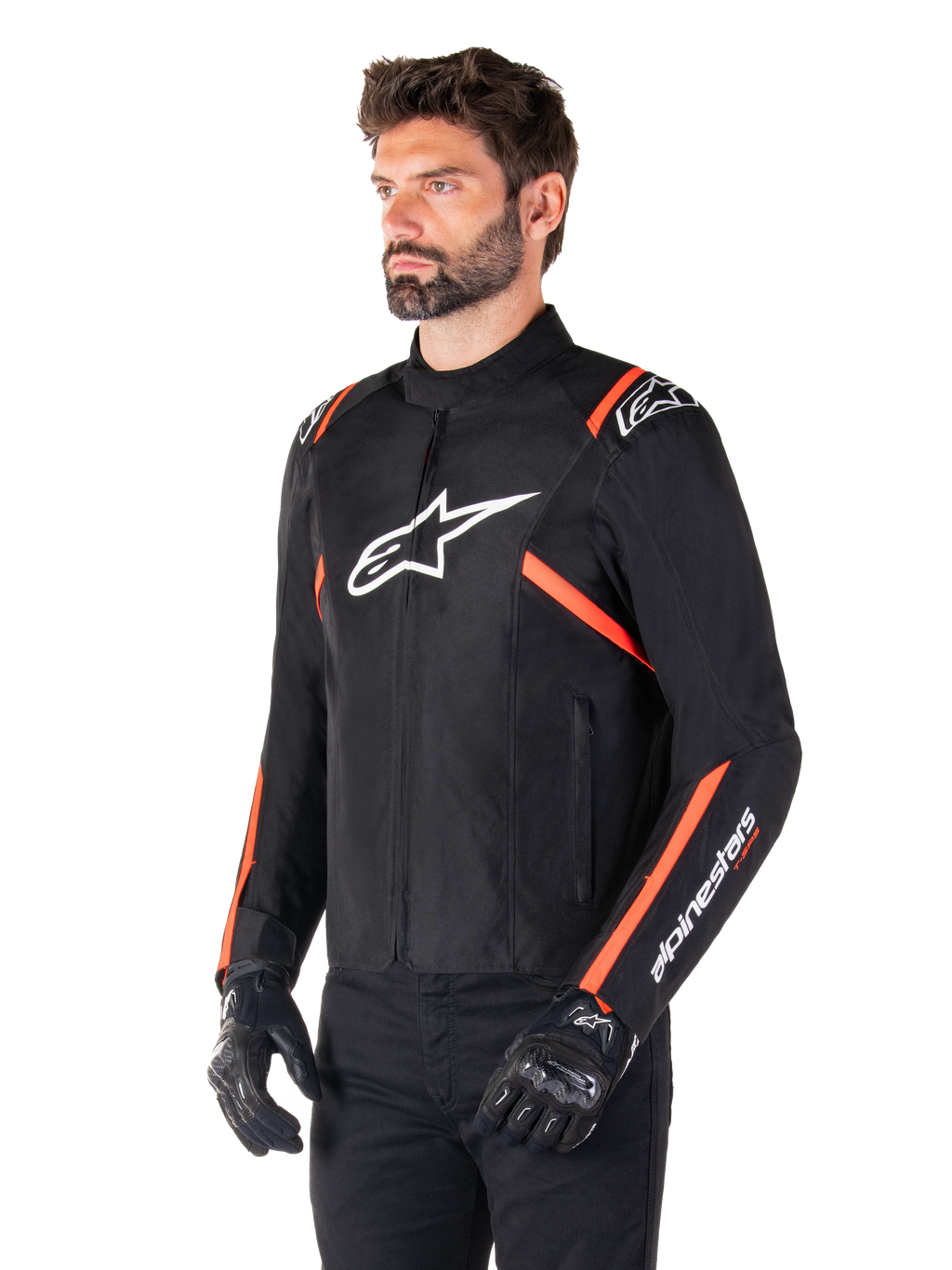 Chaqueta impermeable Alpinestars T-SPS V2, negro, blanco y rojo fluorescente, usada por un modelo masculino con guantes y pantalones negros, con logo blanco de Alpinestars en el pecho y detalles en rojo fluorescente en hombros y mangas, diseño textil deportivo