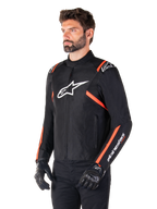 Chaqueta impermeable Alpinestars T-SPS V2, negro, blanco y rojo fluorescente, usada por un modelo masculino con guantes y pantalones negros, con logo blanco de Alpinestars en el pecho y detalles en rojo fluorescente en hombros y mangas, diseño textil deportivo
