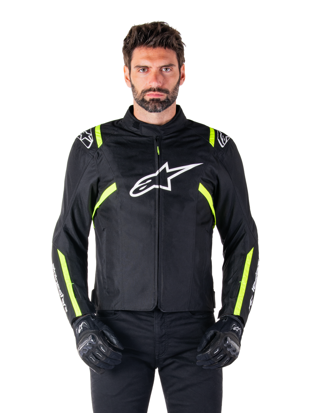 Alpinestars T-SPS V2 Waterproof Jacket, chaqueta de moto, negra con detalles en blanco y amarillo flúor, usada por un modelo con guantes negros, con el logo de la estrella blanca en el pecho y franjas amarillo neón en las mangas y hombros, equipamiento textil deportivo para cualquier clima