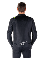 Chaqueta impermeable Alpinestars T-SPS V2, vista posterior, negra con detalles en amarillo flúor en los hombros y logotipo de estrella blanco en la parte inferior de la espalda, chaqueta de moto textil con silueta deportiva, usada por un modelo masculino.