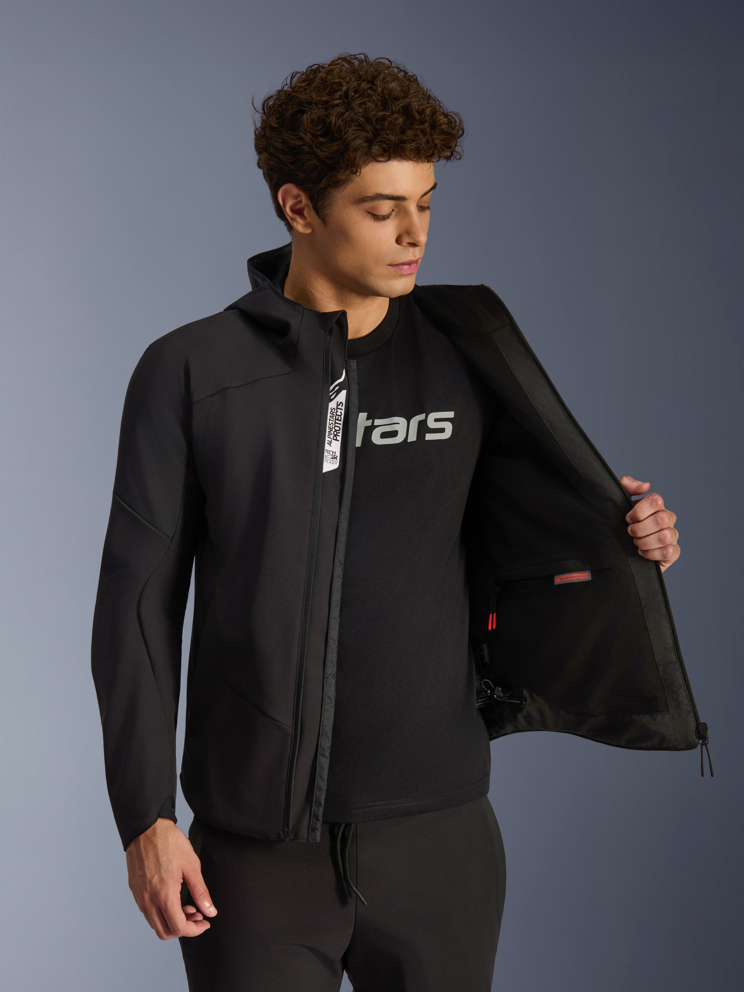 Chaqueta Alpinestars Aeroshell Impermeable para hombre, negra, softshell urbana abierta mostrando el bolsillo interior.