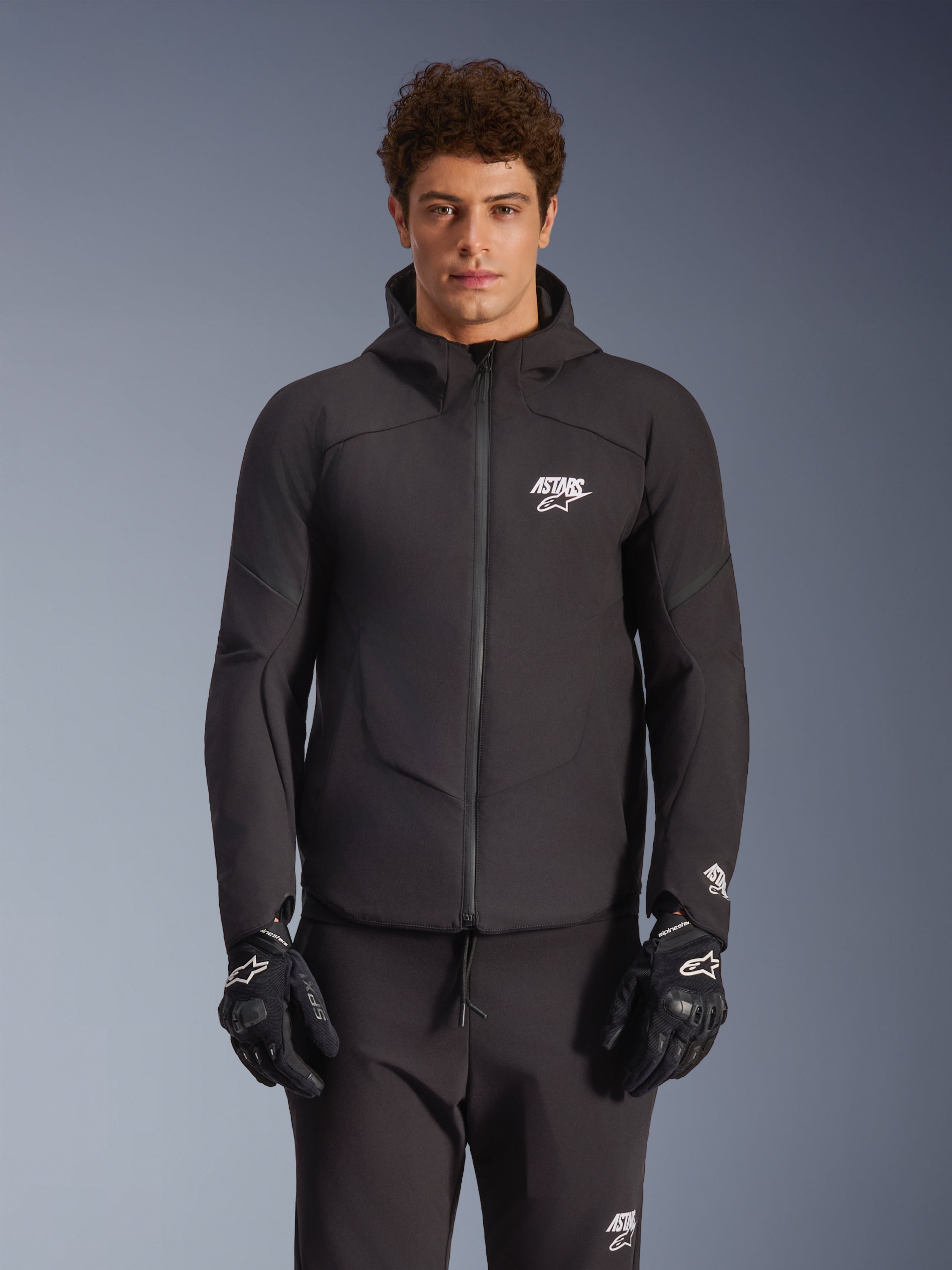 Chaqueta Alpinestars Aeroshell Impermeable, chaqueta de moto urbana para hombre, negra, textil softshell con capucha integrada y logotipos blancos.