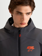 Alpinestars Aeroshell Waterproof Jacket, Men's Motorcycle Sport Softshell Jacket in Black and Dark Gray, featuring an open-slot hood and orange ASTARS logo detail, close-up on model