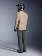 Chaqueta Alpinestars Borrego Drystar®, chaqueta de aventura para motociclista en color Warm Gray, vista trasera del piloto con pantalones gris oscuro y casco negro, con un aspecto robusto de lona encerada y diseño funcional.