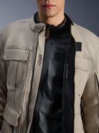 Chaqueta Alpinestars Borrego Drystar® en color Warm Gray, vista de cerca que muestra el frontal abierto, forro interno negro y detalles técnicos interiores que incluyen 'ALPINESTARS PROTECTS' y compatibilidad con protector de pecho, estilo de moto de aventura robusto.