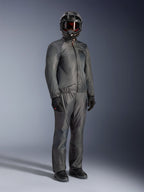 Piloto con la chaqueta Alpinestars Borrego Drystar® en gris cálido, equipamiento de aventura completo con pantalones grises a juego, casco integral negro con gafas y guantes negros, con un elegante diseño textil impermeable.