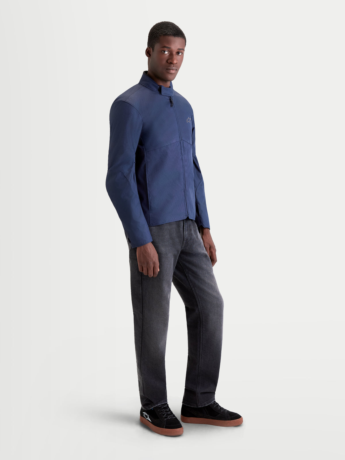 Alpinestars C-1 Waterproof Jacket, men's urban contemporary motorcycle textile jacket in dark blue, side profile view on a model wearing dark pants and casual riding shoes.