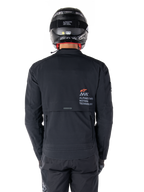 Chaqueta Alpinestars AMT-8 Stretch Drystar® XF, vista trasera, negra, usada con casco y pantalones negros, con el logotipo Alpinestars Motion Technology en la parte posterior, diseño de adventure touring con material elástico ergonómico.