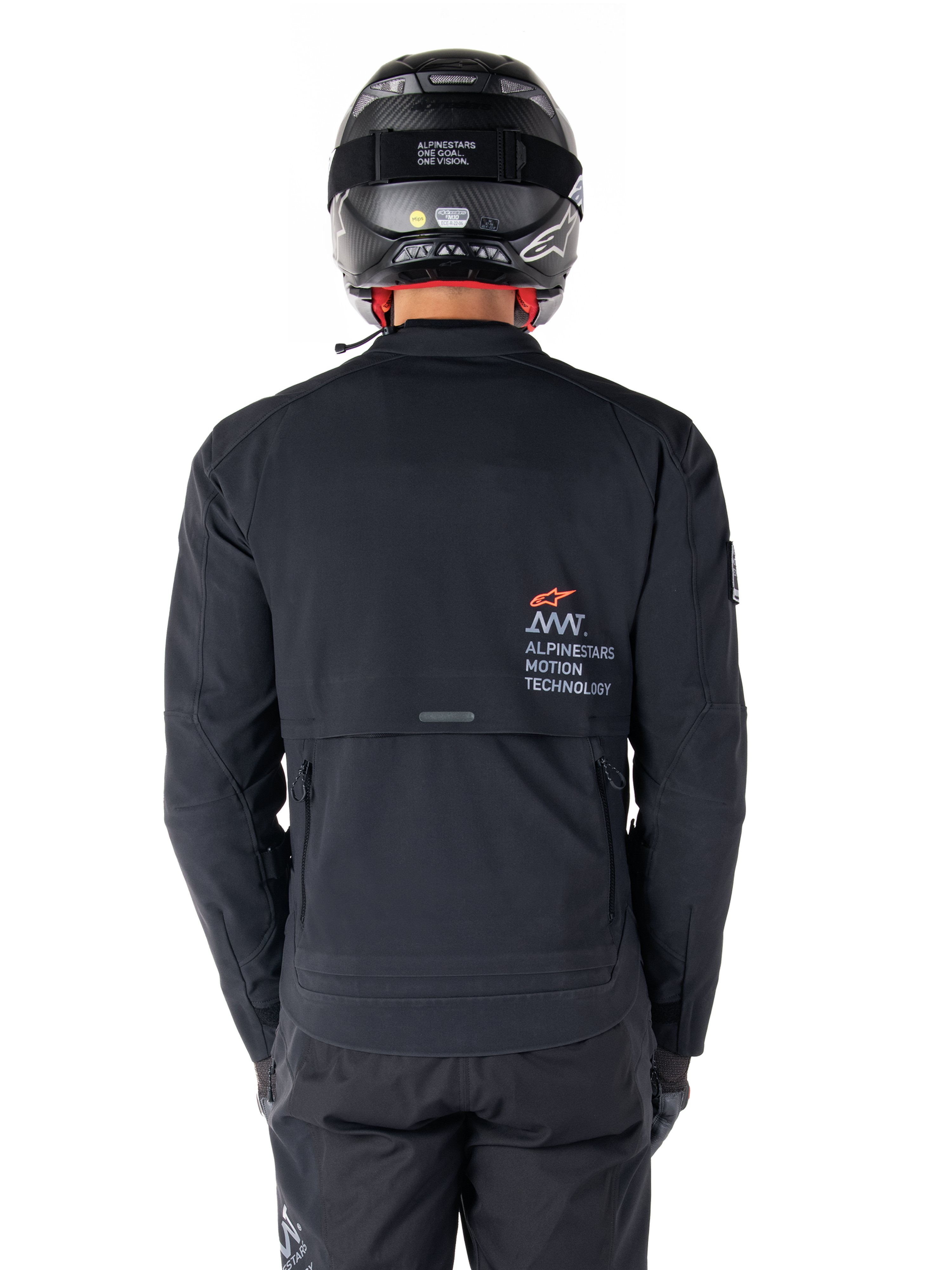 Chaqueta Alpinestars AMT-8 Stretch Drystar® XF, vista trasera, negra, usada con casco y pantalones negros, con el logotipo Alpinestars Motion Technology en la parte posterior, diseño de adventure touring con material elástico ergonómico.
