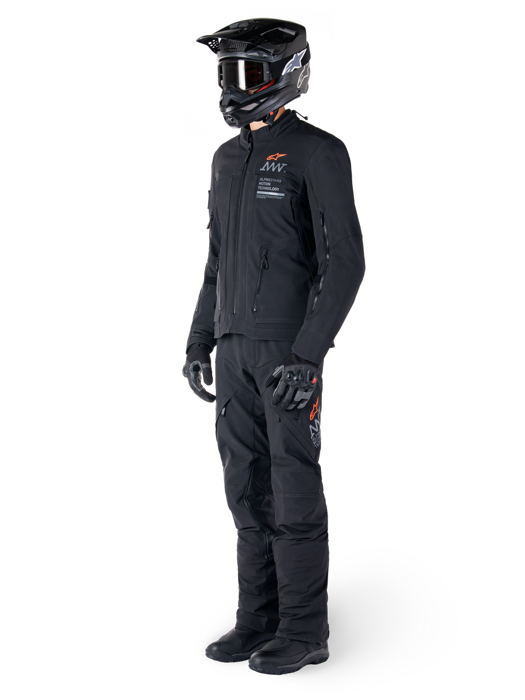 Chaqueta Alpinestars AMT-8 Stretch Drystar® XF, chaqueta de moto de aventura, negra, usada con pantalones a juego, casco y guantes, con la marca Alpinestars Motion Technology y detalles en naranja, construcción elástica duradera para conducción de aventura