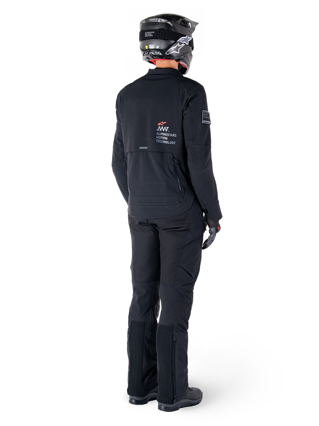 Chaqueta Alpinestars AMT-8 Stretch Drystar® XF, negro, vista trasera de un piloto que lleva la chaqueta con pantalones negros a juego y casco negro, con la marca 'Alpinestars Motion Technology' en la espalda, material elástico técnico para conducción de aventura