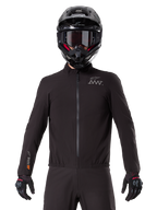 Forro Alpinestars AMT-8 Stretch Drystar® XF, forro de motocicleta impermeable negro, con cremallera frontal y cintura elástica, logotipo AMT en el pecho y marca Drystar XF en la manga, usado con casco y guantes negros.