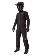 Forro Alpinestars AMT-8 Stretch Drystar® XF, traje de moto impermeable negro, usado con casco, gafas y guantes negros, con logotipos de AMT y Drystar XF, equipamiento de aventura funcional para protección en cualquier condición climática.