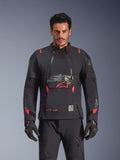 Alpinestars Halo Pro Drystar® XF Laminated Jacket, chaqueta de moto de aventura, color negro Dark Shadow con detalles en rojo, modelo masculino con equipamiento técnico completo incluyendo guantes y pantalones a juego, vista frontal destacando los paneles modulares de ventilación en el pecho y la construcción impermeable.