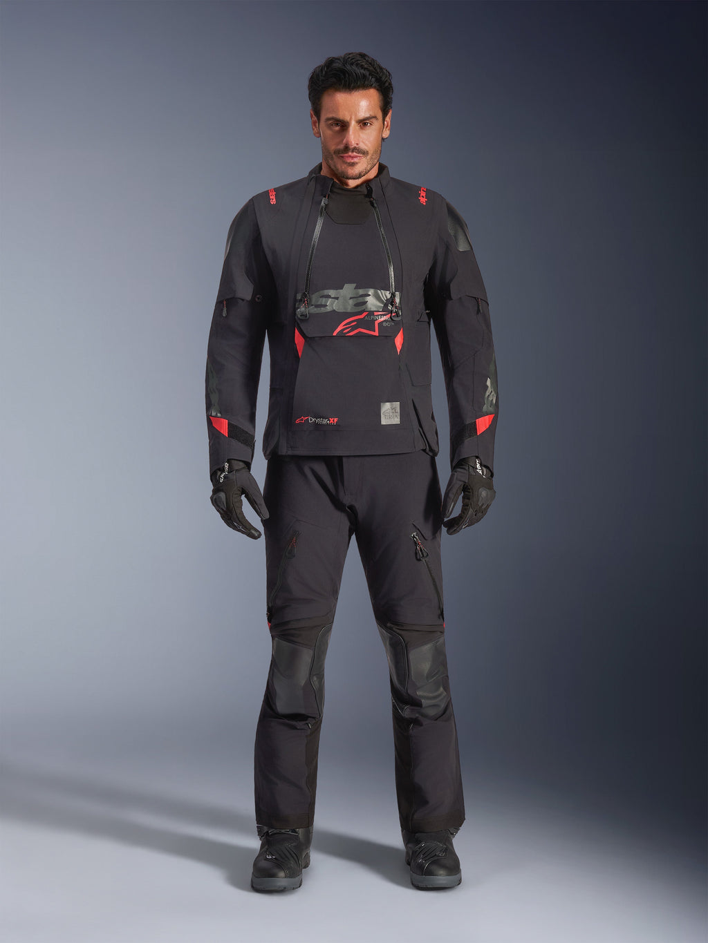 Chaqueta laminada Alpinestars Halo Pro Drystar® XF, negro Dark Shadow con detalles en rojo, conjunto de equipamiento de moto de aventura que incluye pantalones y guantes a juego, diseño textil modular con paneles de ventilación frontales y logo prominente en el pecho.