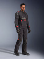 Piloto con la chaqueta laminada Alpinestars Halo Pro Drystar® XF en Black Dark Shadow, equipamiento de aventura completo con pantalones, guantes y botas a juego, paneles frontales asimétricos modulares y detalles rojos de la marca.