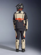 Chaqueta laminada Alpinestars Halo Pro Drystar® XF, chaqueta de aventura para moto, Mastic Black, vista trasera de un piloto con pantalones a juego y un casco negro, con llamativa marca Alpinestars en naranja y paneles de ventilación modulares para una conducción de aventura versátil.