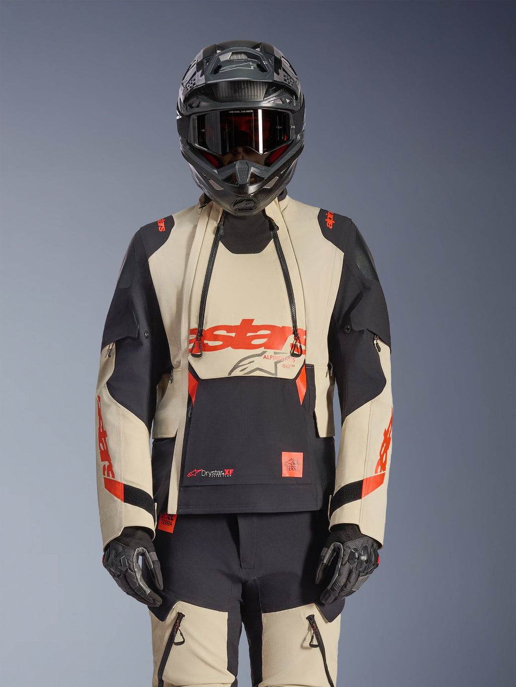 Chaqueta laminada Alpinestars Halo Pro Drystar XF, chaqueta de moto de aventura en color Mastic Black y beige con detalles rojos, usada con equipo de protección completo incluyendo casco y guantes, con paneles de ventilación modulares y construcción laminada 3L.