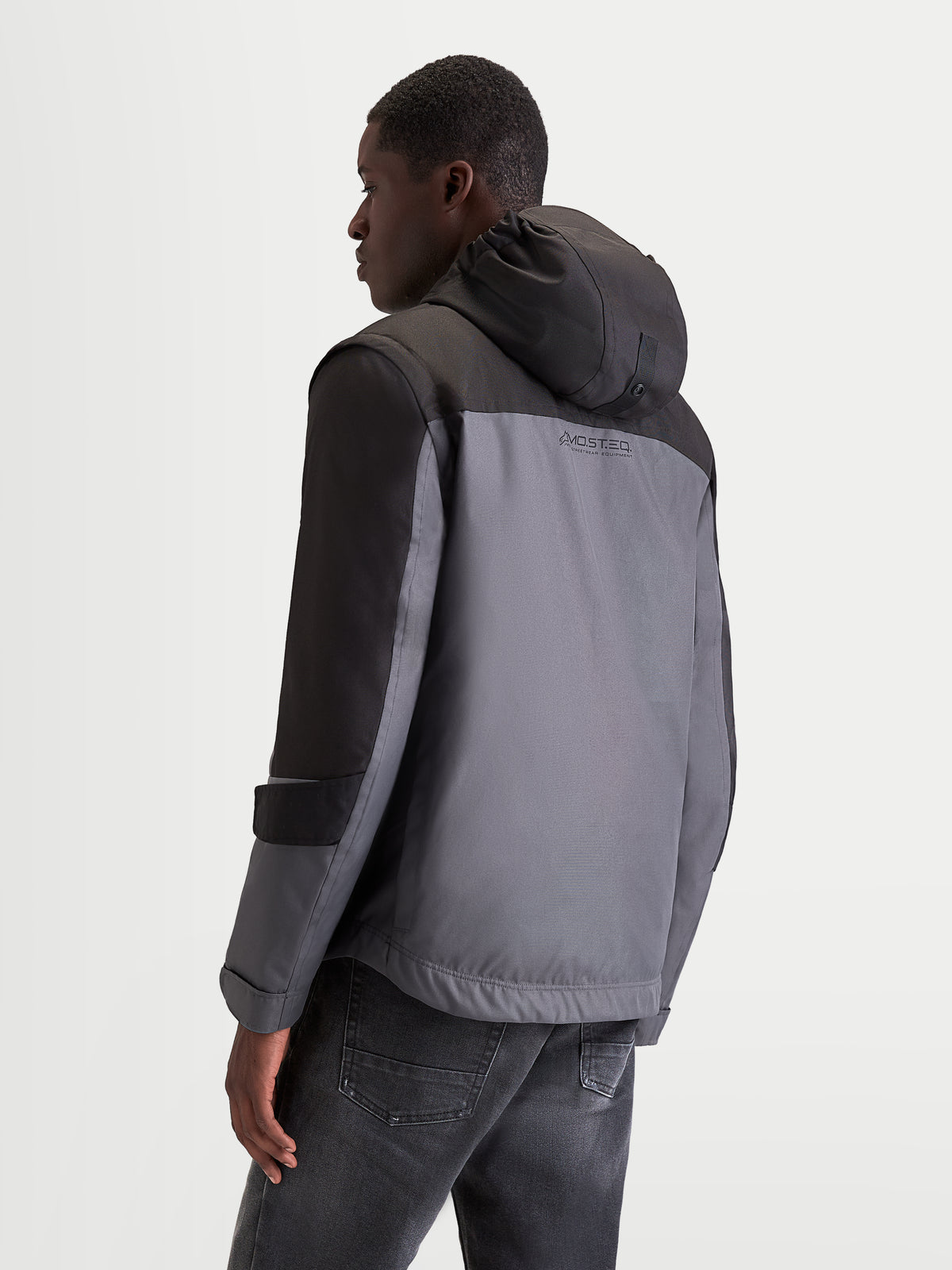 Alpinestars Morfex Parka Wp Chaqueta, chaqueta de moto urbana contemporánea para hombre en gris lunar y negro, vista de perfil trasero de tres cuartos que muestra la capucha integrada y la construcción textil impermeable usada por un modelo
