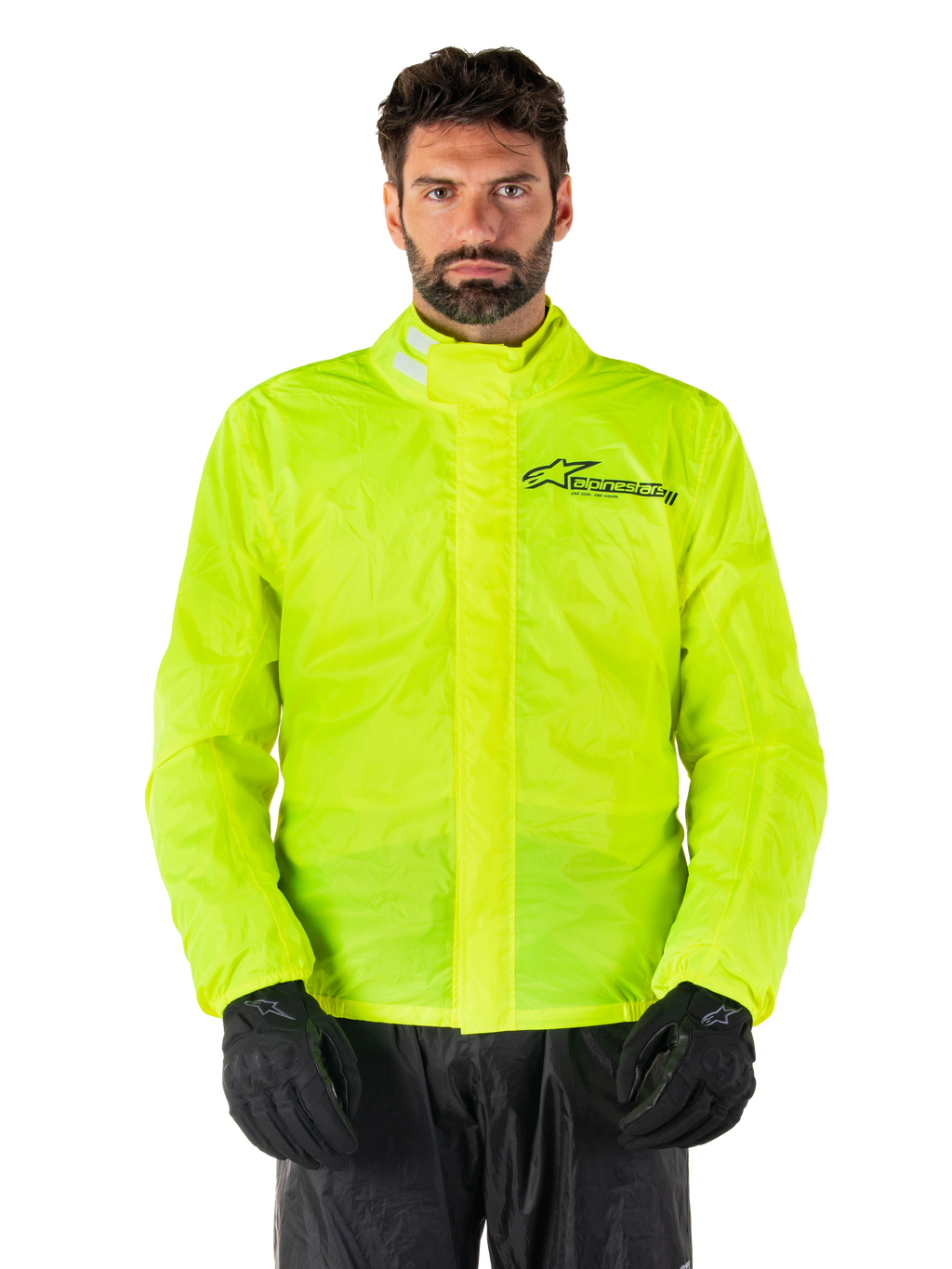Alpinestars Hurricane Rain V2 Jacket, chaqueta impermeable para moto, amarillo flúor, usada por un modelo con pantalones y guantes negros, cuello alto con pestañas reflectantes, solapa frontal contra tormentas con el logo de Alpinestars, equipo impermeable de alta visibilidad