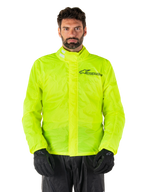 Alpinestars Hurricane Rain V2 Jacket, chaqueta impermeable para moto, amarillo flúor, usada por un modelo con pantalones y guantes negros, cuello alto con pestañas reflectantes, solapa frontal contra tormentas con el logo de Alpinestars, equipo impermeable de alta visibilidad