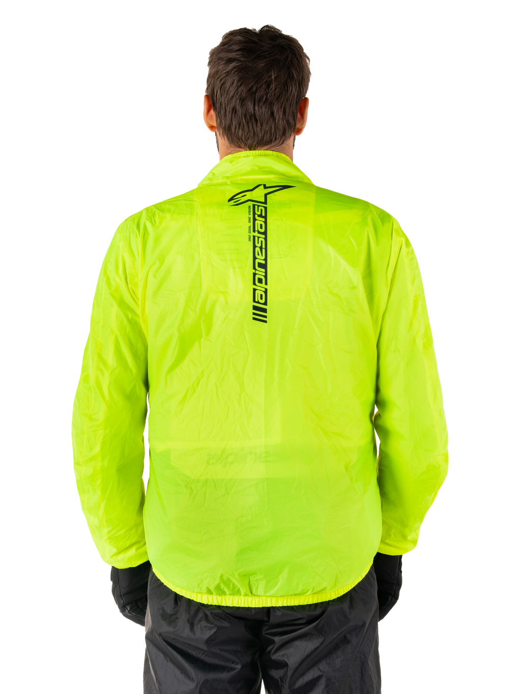 Chaqueta Alpinestars Hurricane Rain V2, chaqueta impermeable para moto, amarillo flúor, vista trasera que muestra el logotipo vertical negro de Alpinestars en el centro de la espalda, tejido impermeable ligero, usada con pantalones de moto y guantes negros