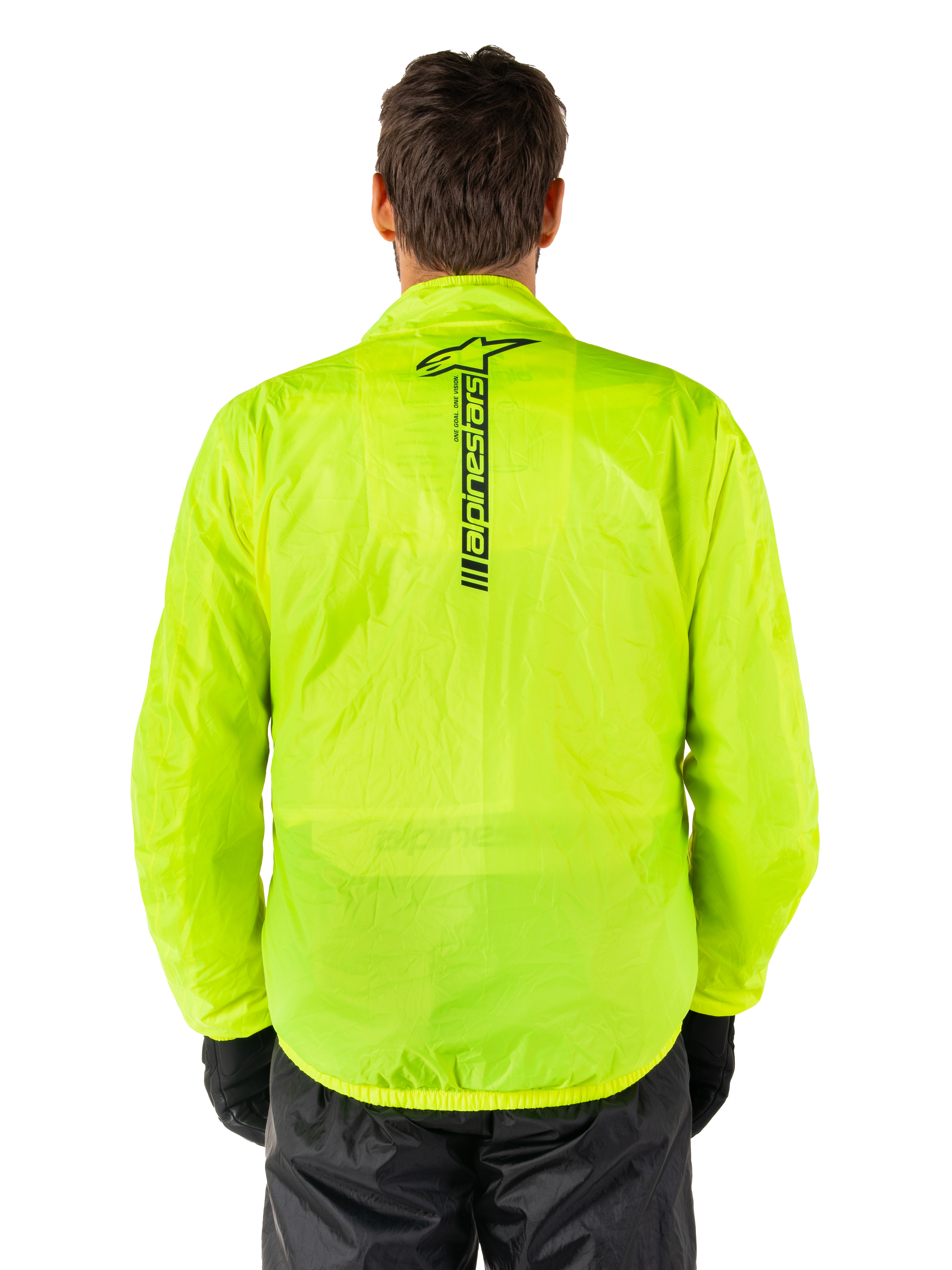 Chaqueta Alpinestars Hurricane Rain V2, chaqueta impermeable para moto, amarillo flúor, vista trasera que muestra el logotipo vertical negro de Alpinestars en el centro de la espalda, tejido impermeable ligero, usada con pantalones de moto y guantes negros