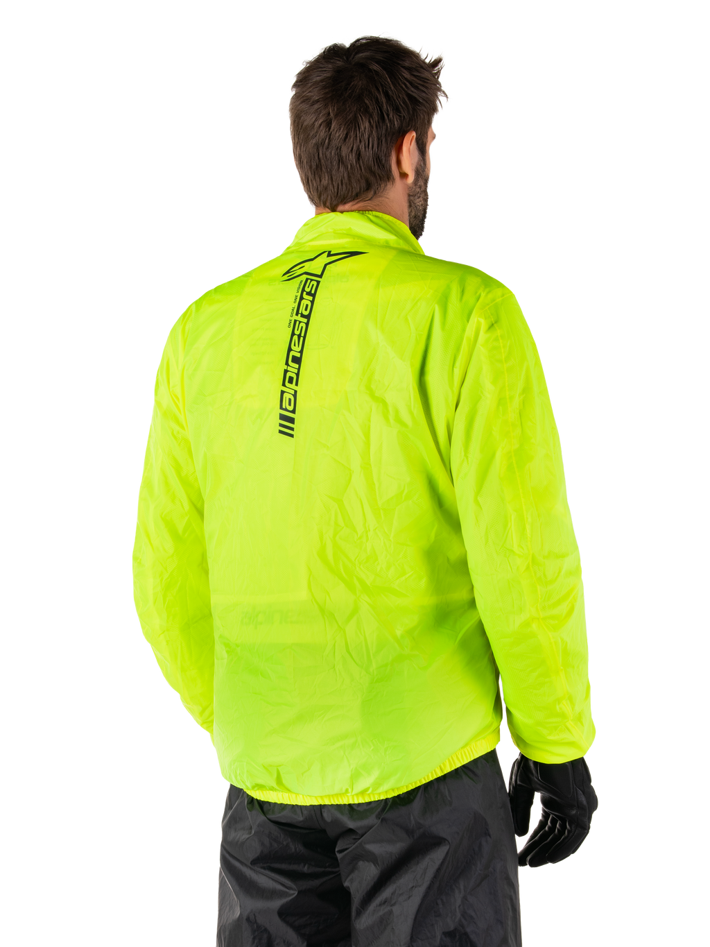 Chaqueta Alpinestars Hurricane Rain V2, Amarillo Fluo, vista trasera en un modelo masculino, con el logotipo vertical de Alpinestars en negro en el centro de la espalda, cintura y puños elásticos, diseño impermeable y plegable