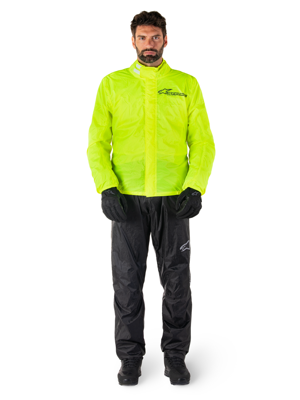 Chaqueta y pantalones Alpinestars Hurricane Rain V2, amarillo neón y negro, traje de lluvia impermeable para motocicleta usado con guantes y botas negras, con el logotipo de Alpinestars en el pecho y la pierna
