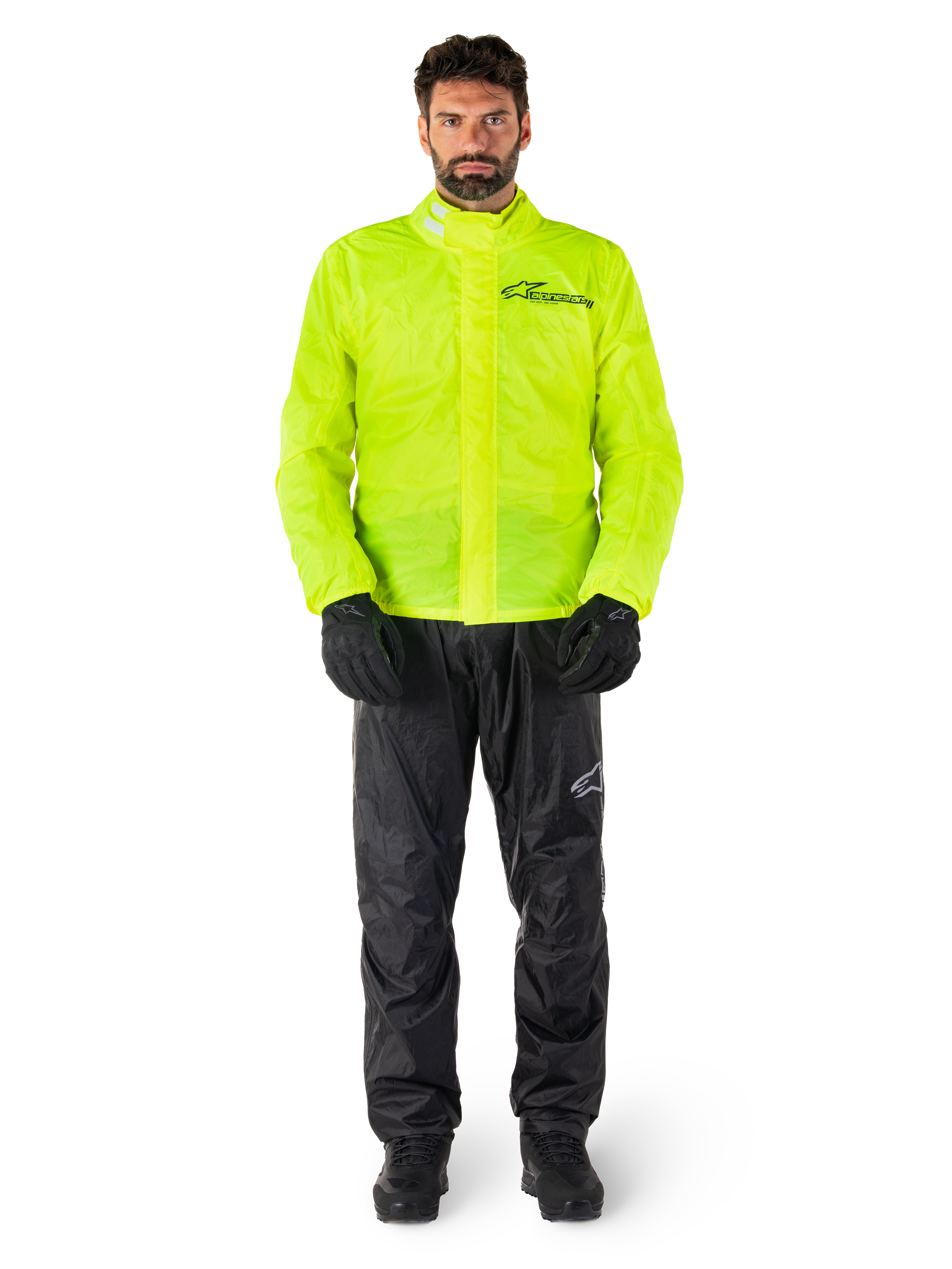 Chaqueta y pantalones Alpinestars Hurricane Rain V2, amarillo neón y negro, traje de lluvia impermeable para motocicleta usado con guantes y botas negras, con el logotipo de Alpinestars en el pecho y la pierna