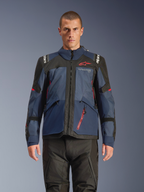 Chaqueta Alpinestars Andes V4 Drystar®, chaqueta de motociclismo de aventura, en azul noche y Mood Indigo con paneles negros, vestida por un modelo con pantalones de moto negros, logotipo de Alpinestars rojo en el pecho y detalle de cremallera roja, construcción textil resistente para touring en todo tipo de clima.