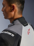 Chaqueta Alpinestars Andes V4 Drystar®, primer plano del cuello y la parte superior de la espalda, gris oscuro y gris hielo con acentos negros, logotipo de estrella roja, con ajustador de cordón en el cuello y marca Alpinestars, construcción textil duradera