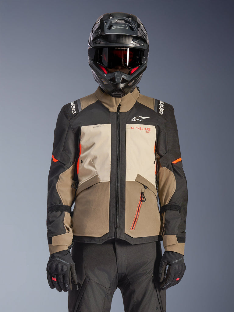 Chaqueta Alpinestars Andes V4 Drystar®, Walnut Mastic Black, chaqueta de adventure touring con paneles en marrón nogal y crema mastic, mangas negras y detalles en naranja brillante, usada con un casco de moto negro, gafas oscuras y guantes negros