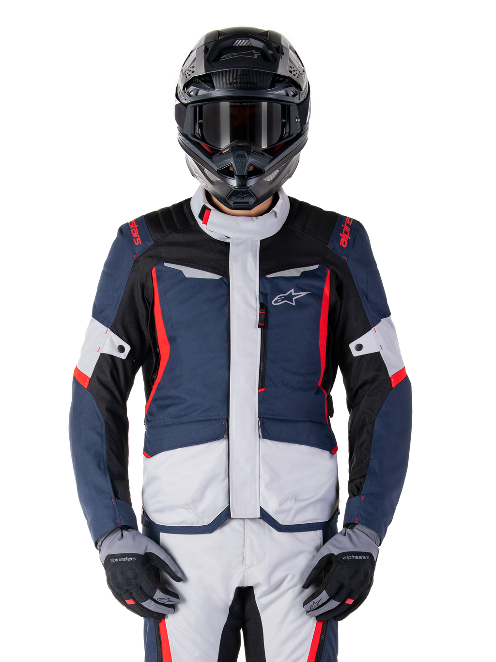 Chaqueta impermeable Alpinestars ST-1, chaqueta de turismo de aventura, azul oscuro, negro y rojo brillante, usada con casco de aventura negro y guantes grises, con paneles en gris claro y detalles rojos en hombros y cremalleras, diseño estilizado con la marca Alpinestars en el pecho, equipo impermeable duradero para motociclismo