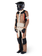 Chaqueta Alpinestars ST-1 Waterproof, Dark Khaki Sand Black Red Fluo, usada por un piloto con equipamiento completo de touring de aventura con pantalones a juego, casco negro, gafas, guantes y botas, conjunto técnico de moto para todo clima
