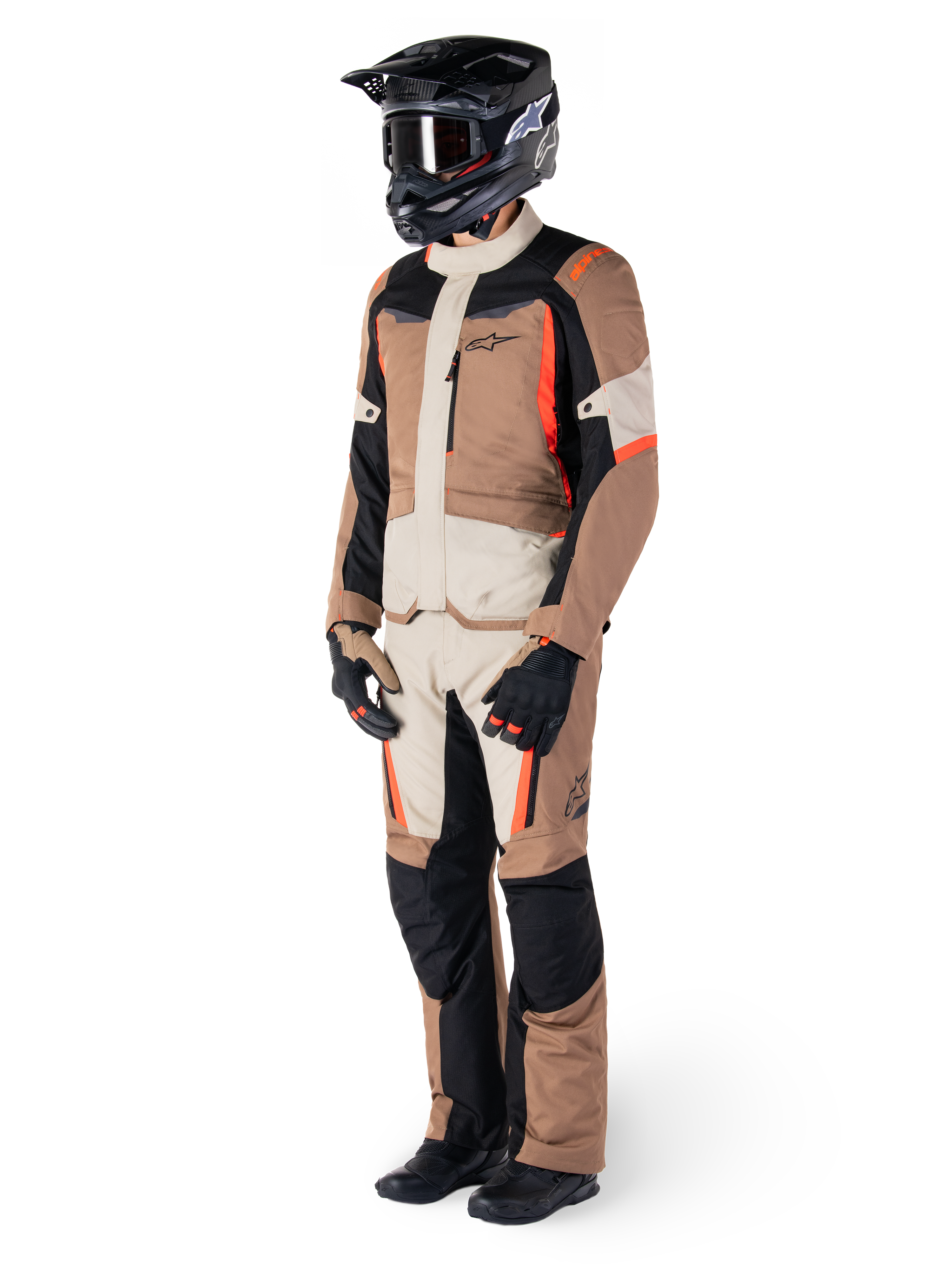 Chaqueta Alpinestars ST-1 Waterproof, Dark Khaki Sand Black Red Fluo, usada por un piloto con equipamiento completo de touring de aventura con pantalones a juego, casco negro, gafas, guantes y botas, conjunto técnico de moto para todo clima